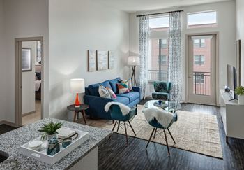 A living room with a blue couch, a chair, and a table with a plant on it.